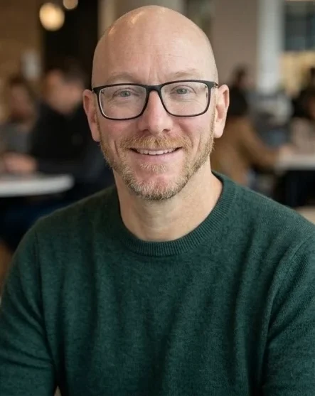 Rick, Co-Founder of Enablement Marketing, smiling in a professional headshot wearing glasses and a dark sweater